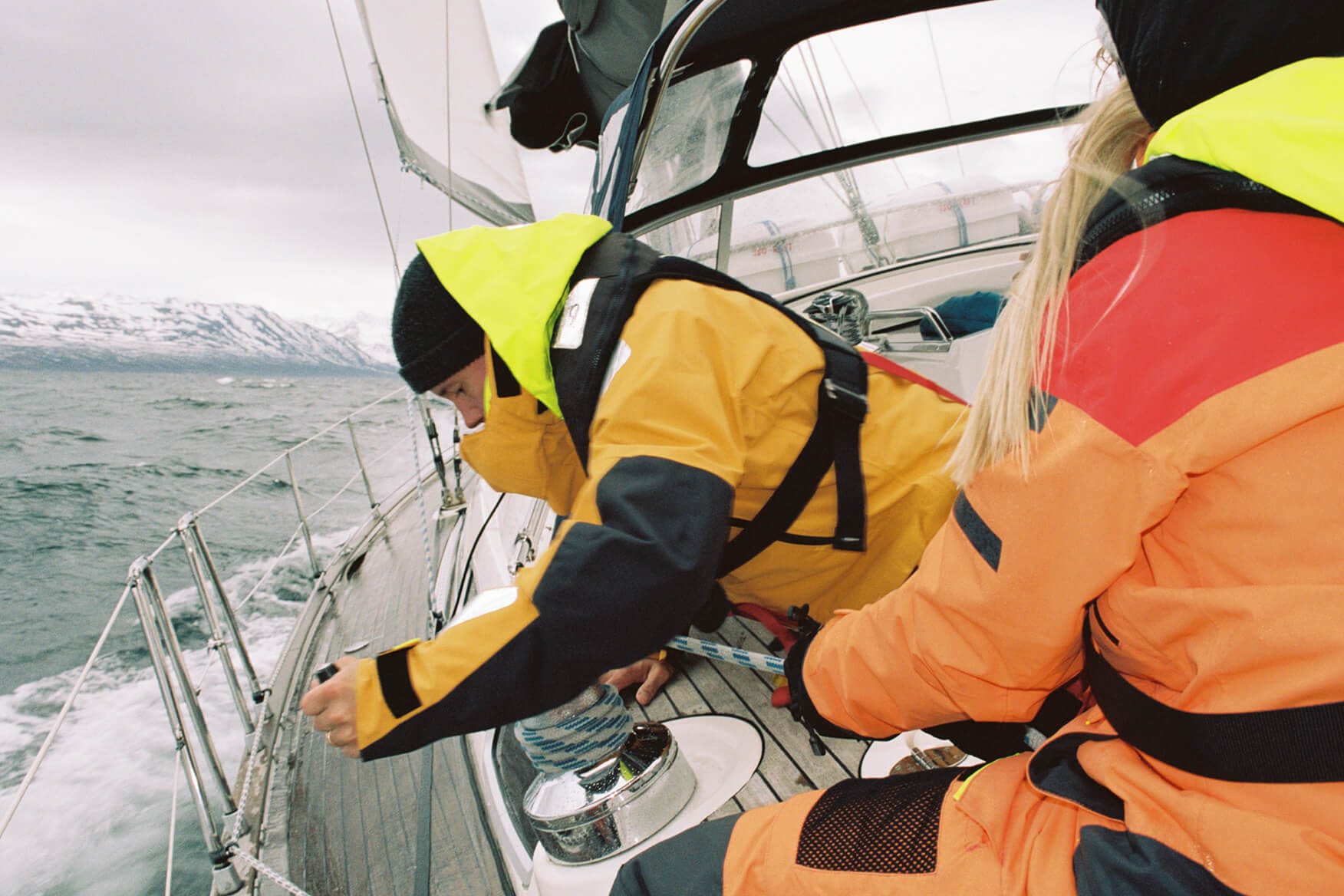 two sailors working the ropes on a sailing boat