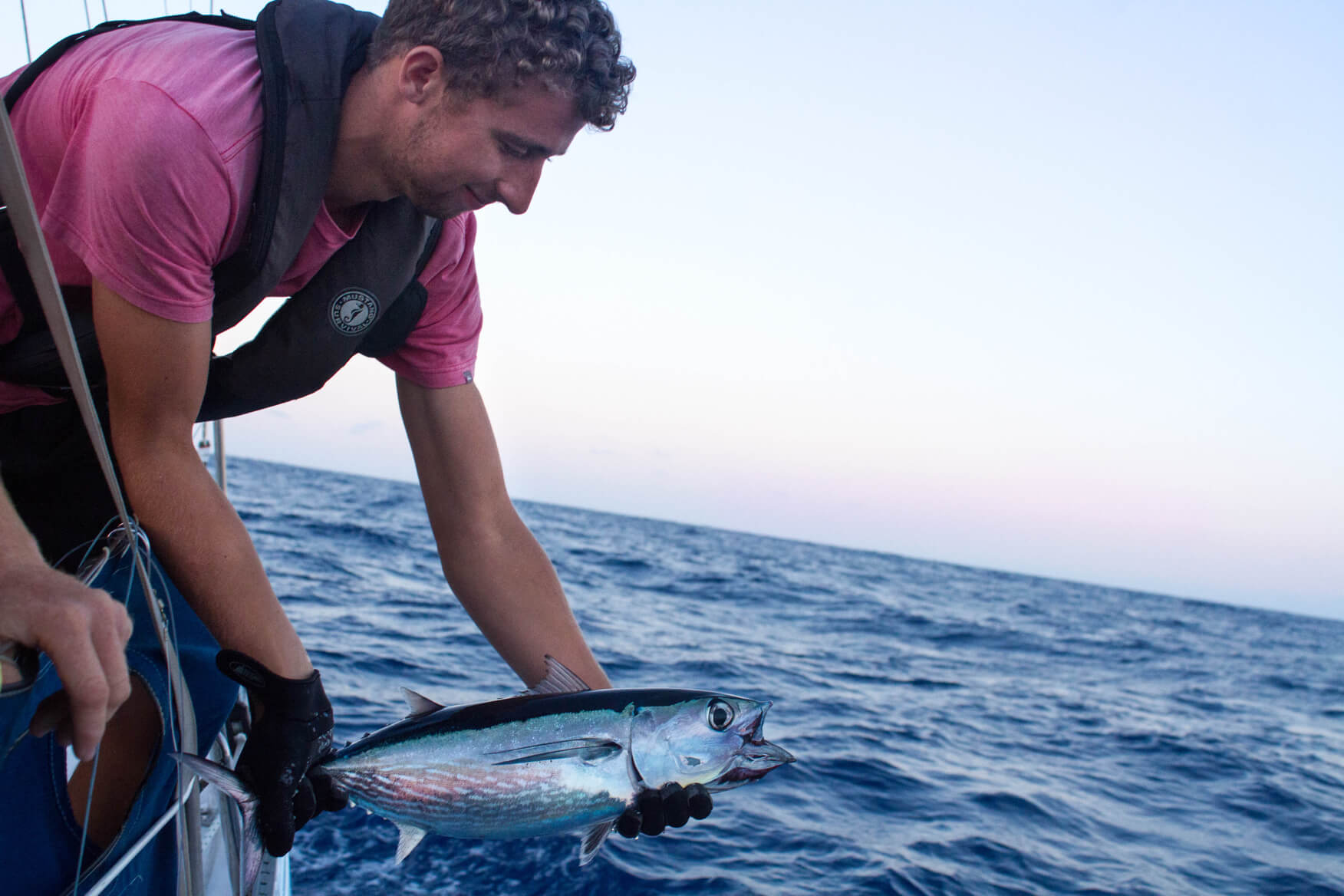 a crew member reeling in a fish from the ocean