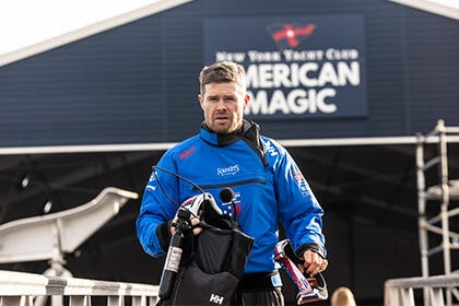 American Magic sailor carrying a helmet