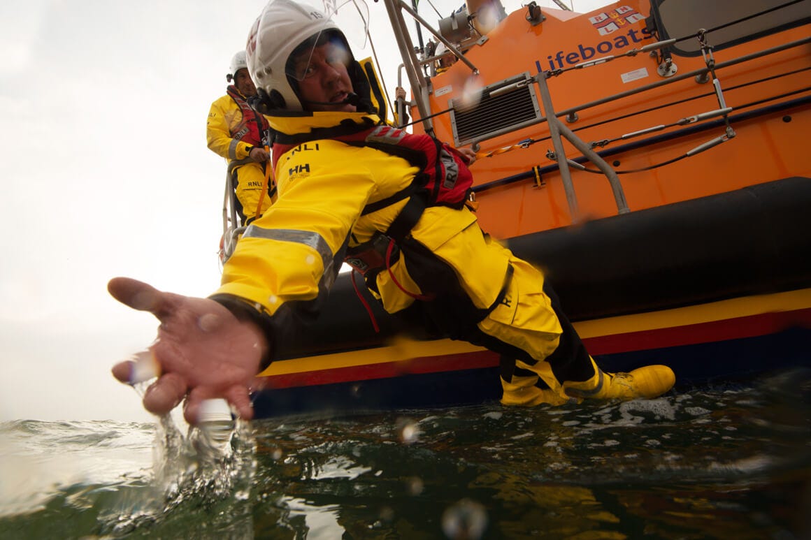 rnli professional reaching down from a rescue boat