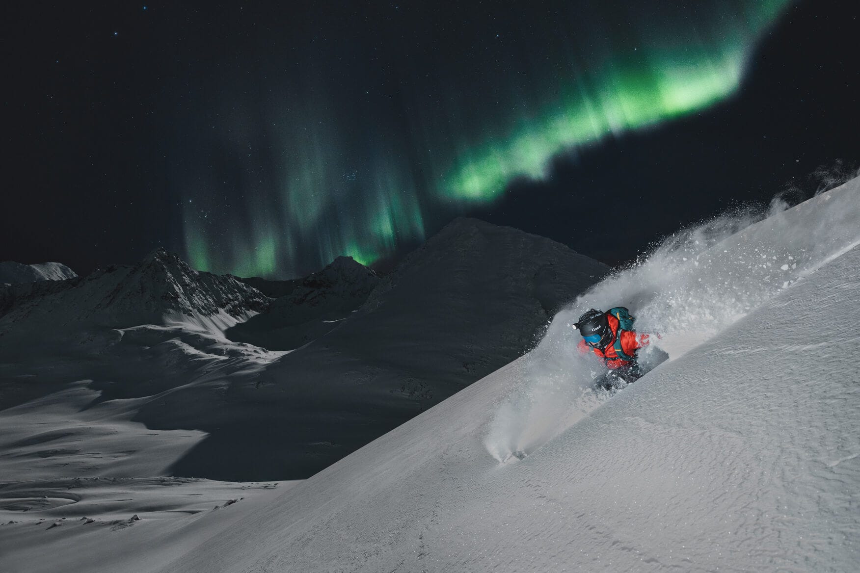 person skiing in fresh powder snow under the northern lights