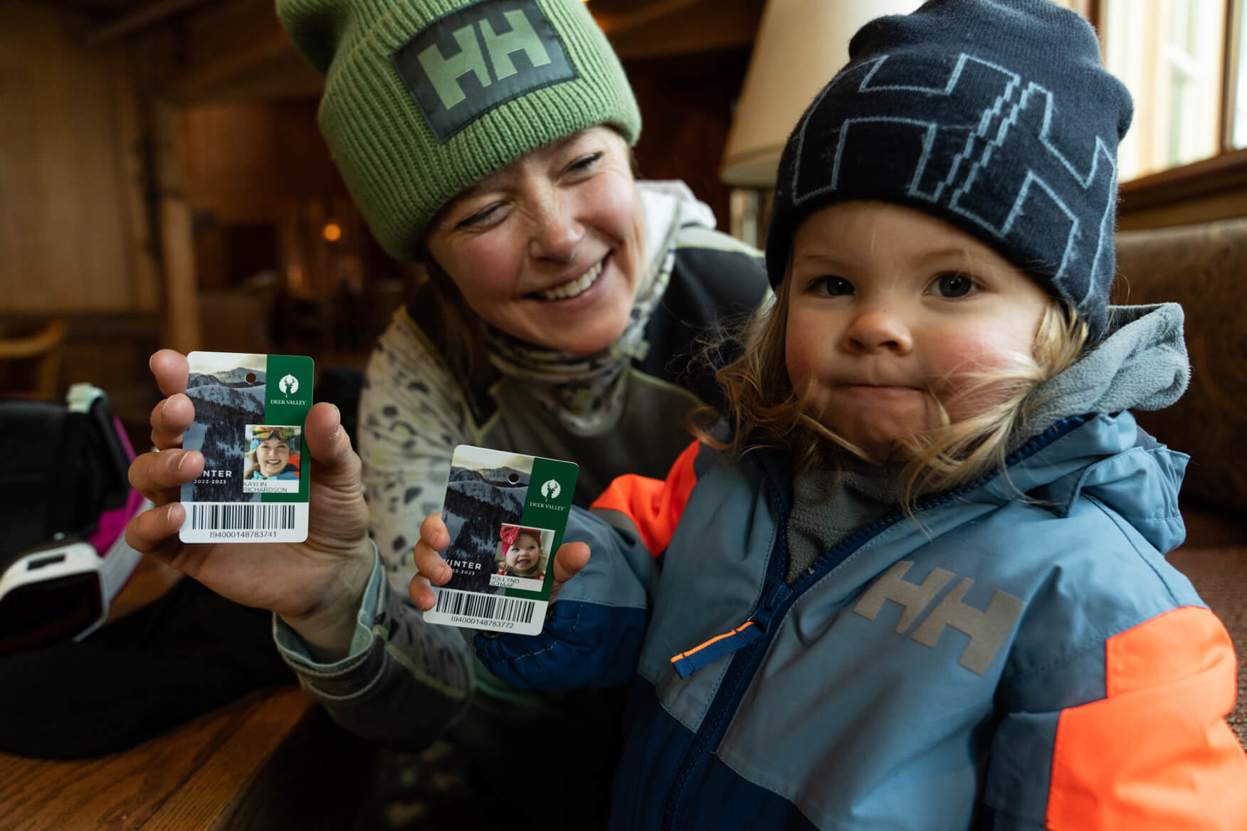 kaylin and her daughter holding ski passes, wearing helly hansen clothing