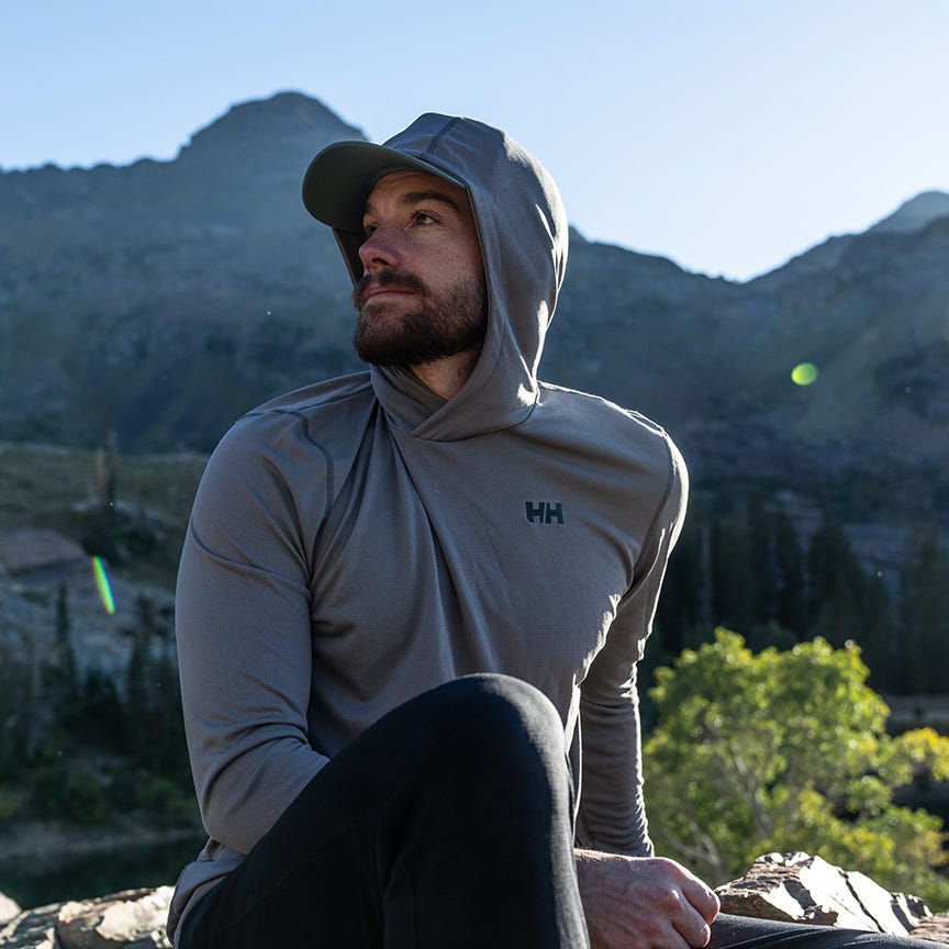 man sitting in nature wearing a hooded synthetic base layer