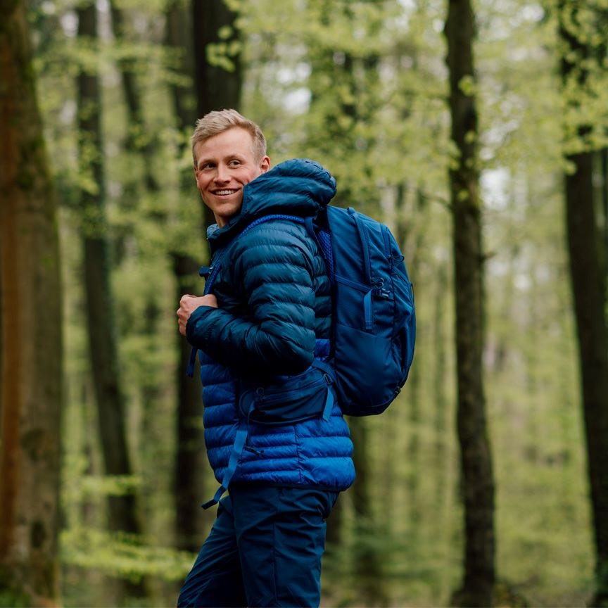 Man hiking through the forest wearing the 20L Generator backpack.