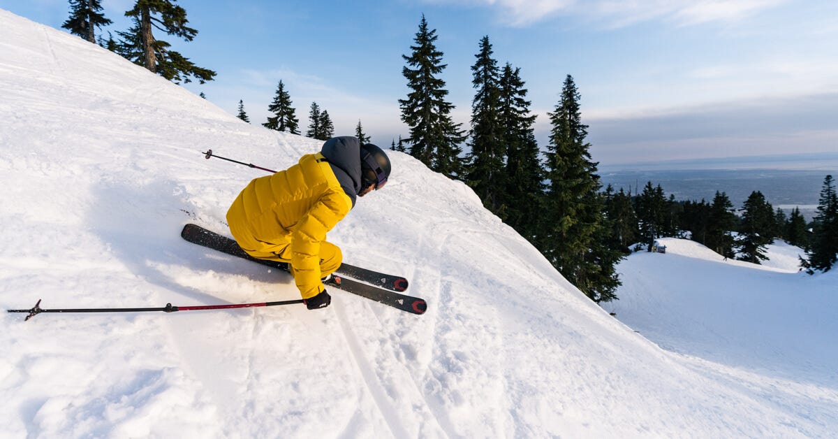 man skiing down a ski slope in yellow helly hansen jacket